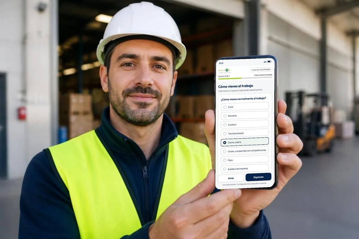 Trabajador con casco y chaleco reflectante respondiendo en el móvil la encuesta de movilidad al trabajo: pregunta «¿Cómo vienes normalmente al trabajo?» con opciones a pie, bicicleta, autobús, tren o coche