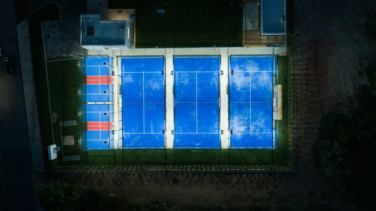 Pistas de pádel iluminadas de noche vistas desde el aire, objeto de un estudio lumínico