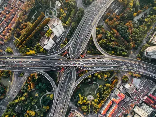 Vista aérea de un intercambiador de autovías y zonas verdes que ilustra la planificación de la movilidad urbana sostenible