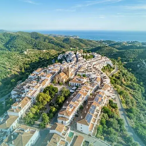 Vista aérea de municipio mediterráneo con placas solares y zonas verdes